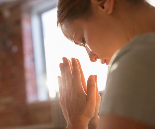 religion, faith and people concept - close up of woman meditating at yoga studio
